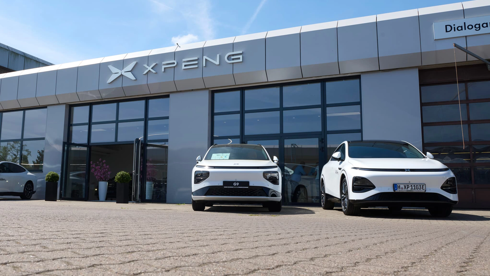 Xpeng Autohaus mit zwei weißen Elektroautos vor dem Gebäude.
