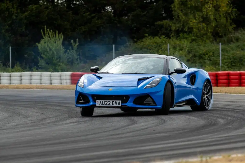 Blauer Lotus Emira Sportwagen in einer Kurve auf einer Rennstrecke.