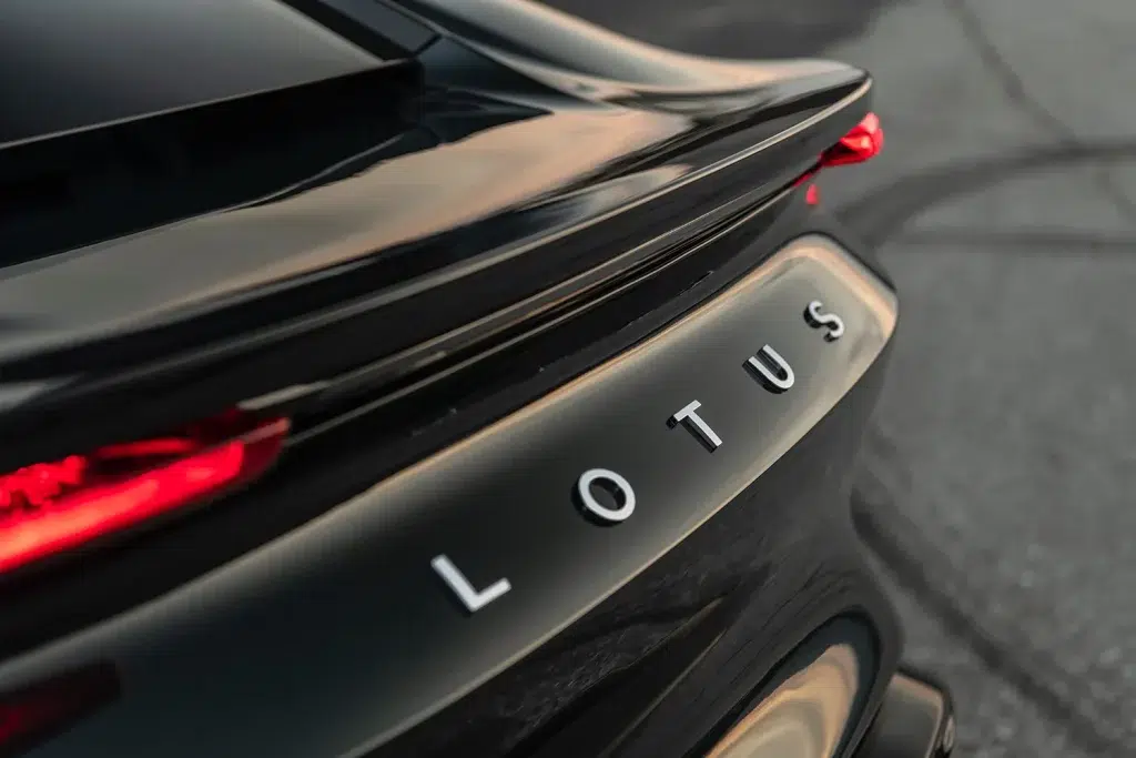 Nahaufnahme des Hecks eines schwarzen Lotus Emira mit silbernem LOTUS-Schriftzug und rotem Rücklicht.