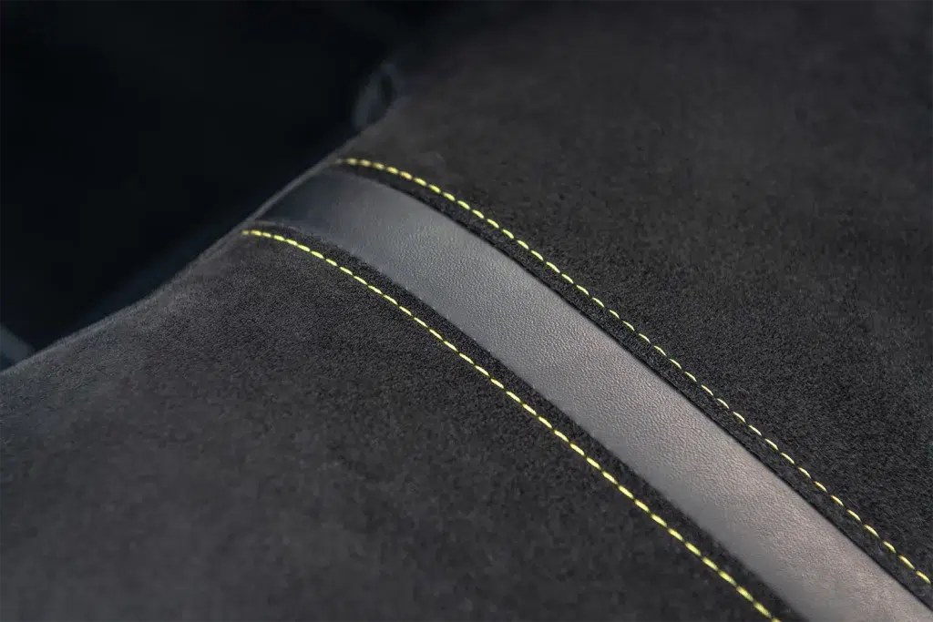 Nahaufnahme eines Emira-Autositzes mit schwarzem Alcantara, Leder und gelben Ziernähten.