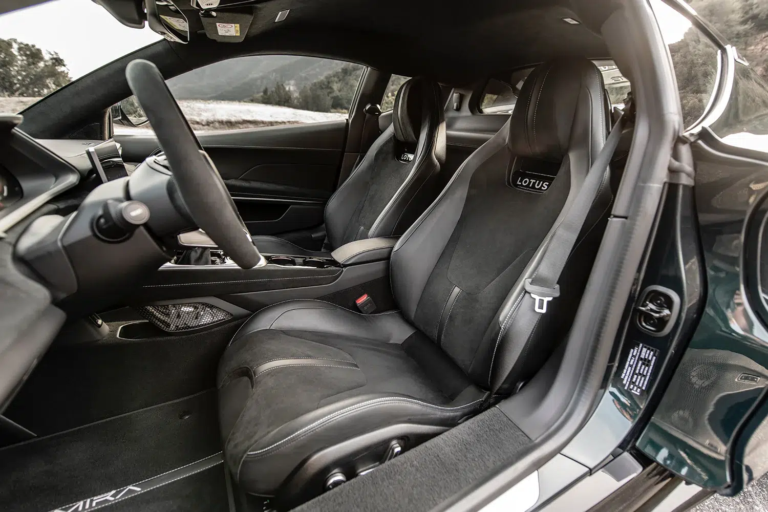 Blick in den schwarzen Innenraum des Lotus Emira mit Sportsitzen, Lenkrad und Armaturenbrett.