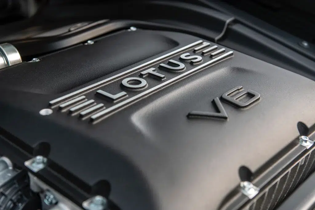 Nahaufnahme der schwarzen V6-Motorabdeckung eines Lotus Emira mit silbernem Lotus-Schriftzug.