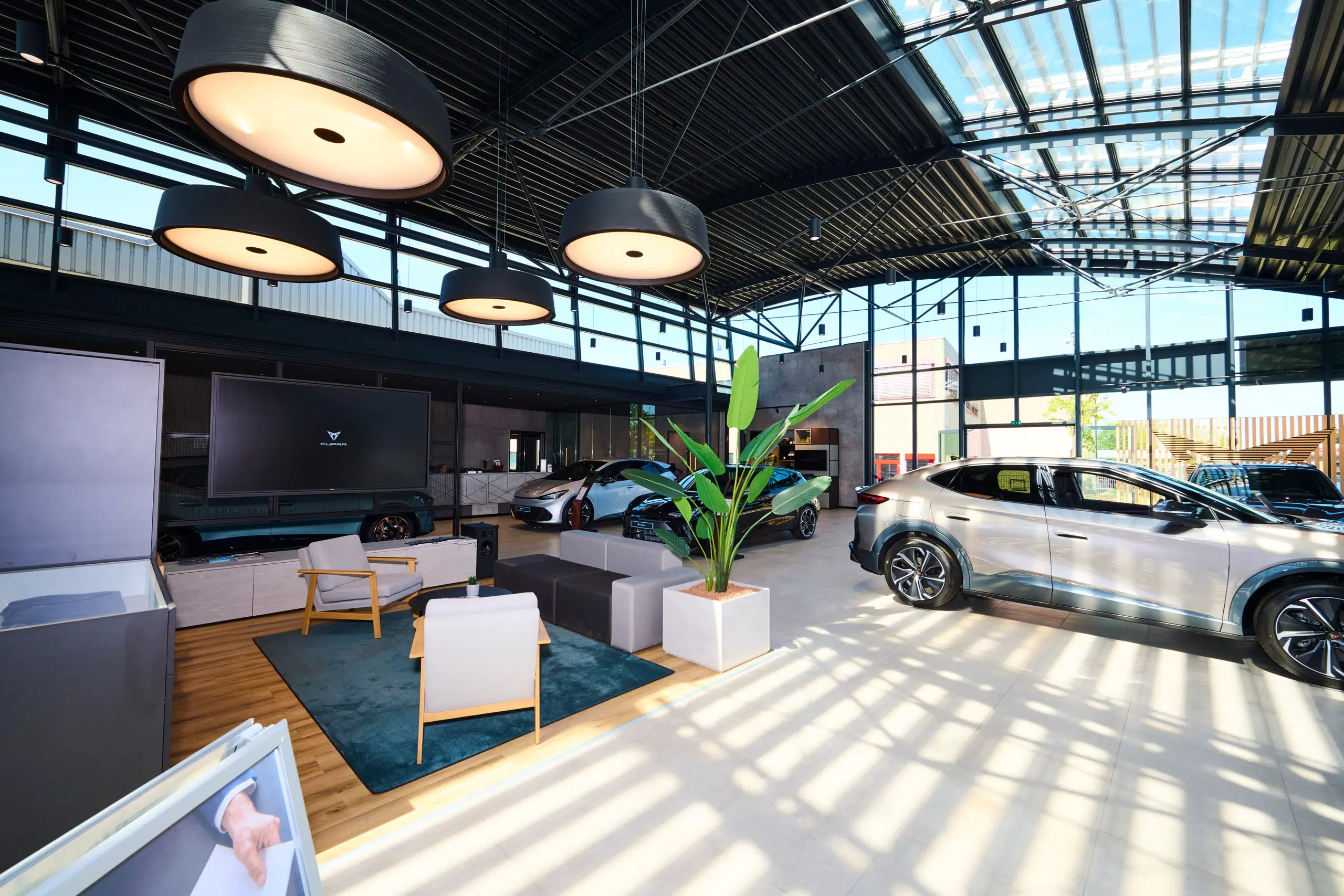 Innenansicht eines modernen Cupra-Autohauses mit mehreren ausgestellten Fahrzeugen und einem Loungebereich.