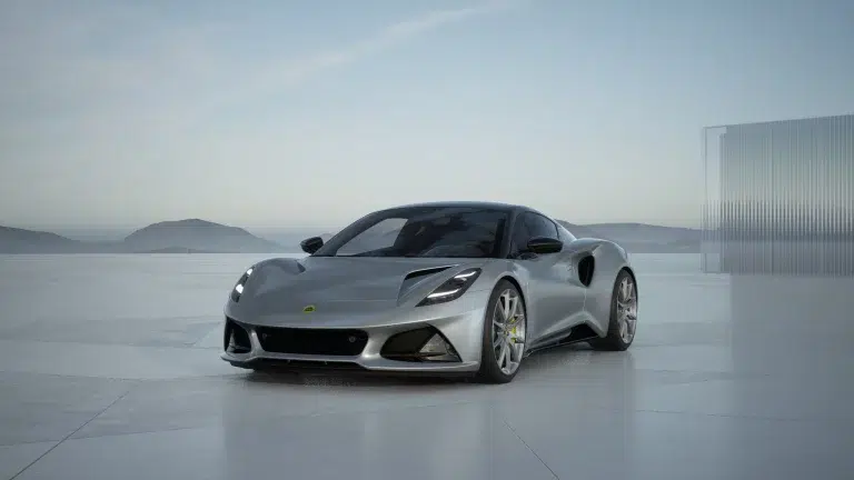 Lotus Emira Turbo SE in Osmium Silber frontal auf hellem Untergrund vor Bergen und Glasstruktur.