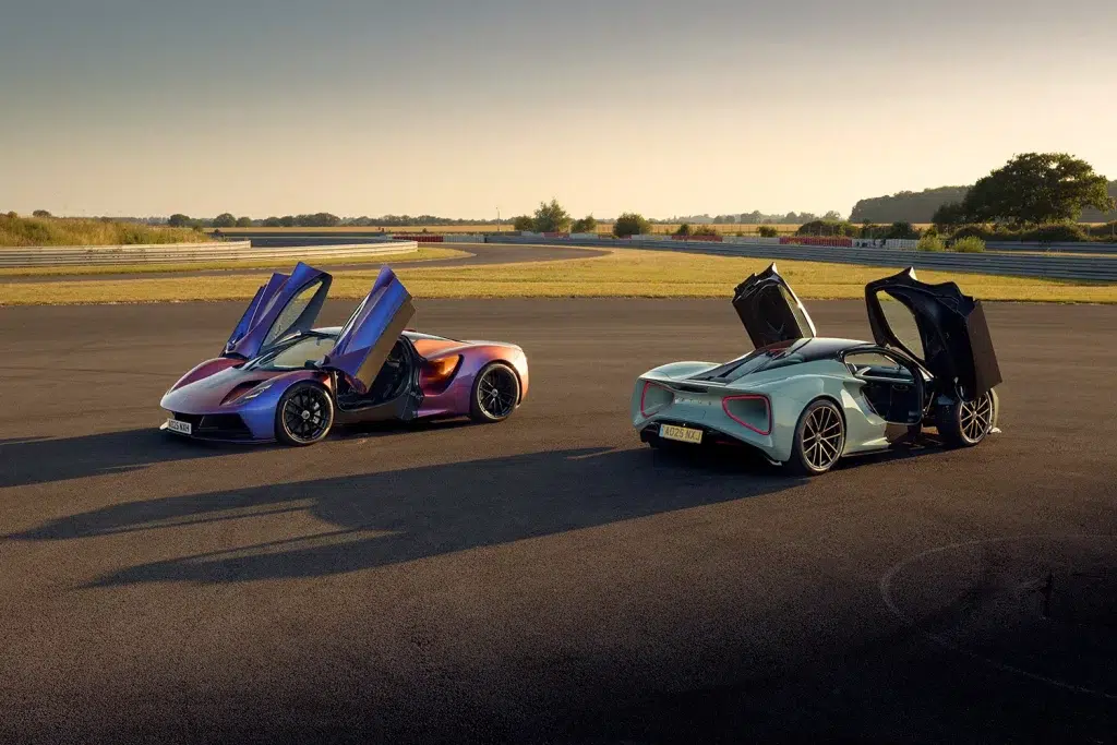 Ein irisierender und ein hellblauer Lotus Evija stehen mit geöffneten Flügeltüren auf einer Rennstrecke.