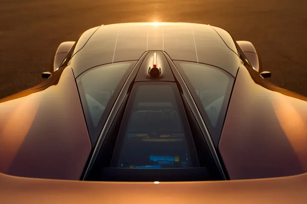 Draufsicht auf das bronzefarbene Heck des Lotus Evija mit sichtbaren Komponenten unter Glas bei Sonnenuntergang