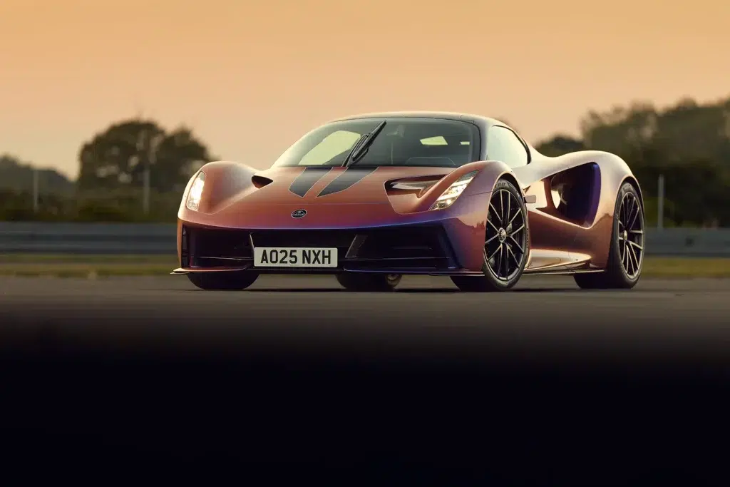 Lotus Evija Hypercar in changierendem Rot-Violett auf einer Rennstrecke bei Sonnenuntergang.