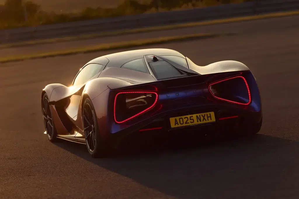 Dunkelvioletter Lotus Evija von hinten-seitlich bei Sonnenuntergang mit leuchtenden roten Rücklichtern.