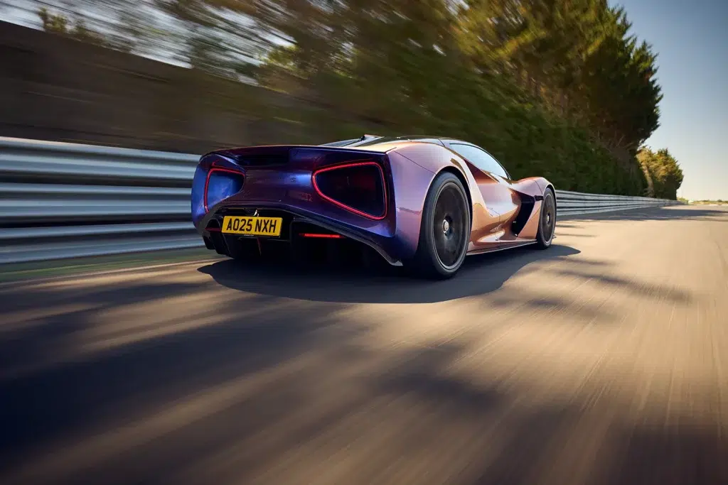 Der blau-violette Lotus Evija fährt mit hoher Geschwindigkeit auf einer Rennstrecke, aus der Heckansicht.