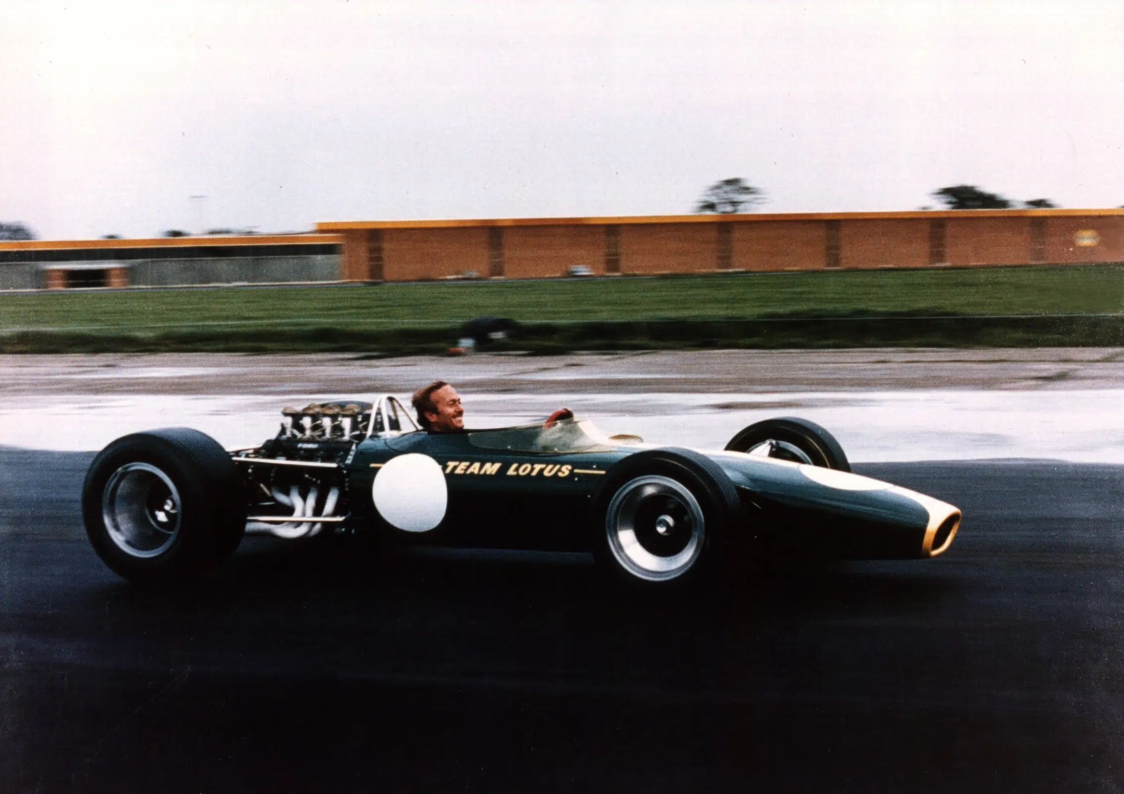 Jim Clark in dunkelgrünem Team Lotus Formel-1-Wagen auf einer Rennstrecke.
