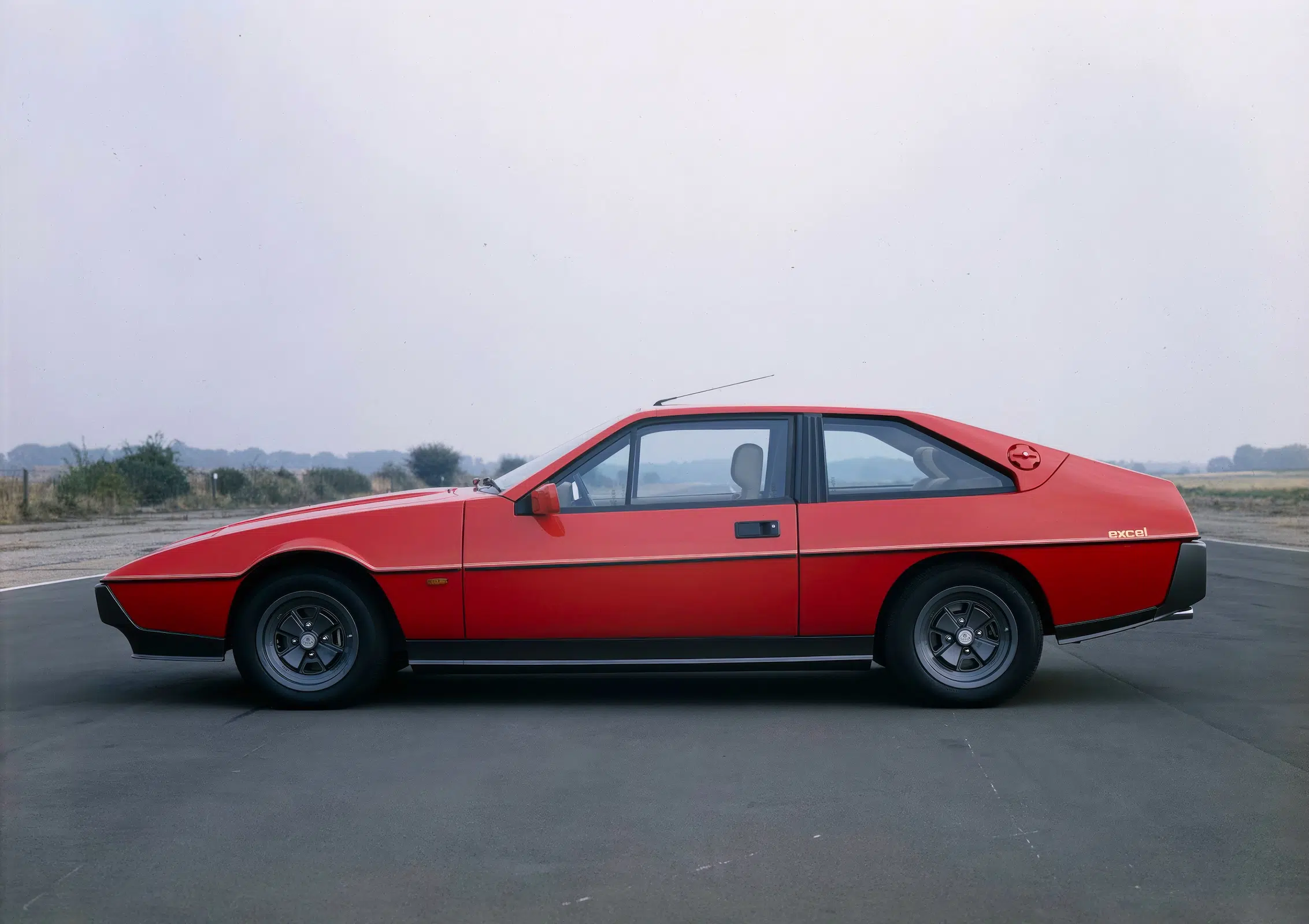 Roter Lotus Excel Sportcoupé in Seitenansicht auf Asphalt.