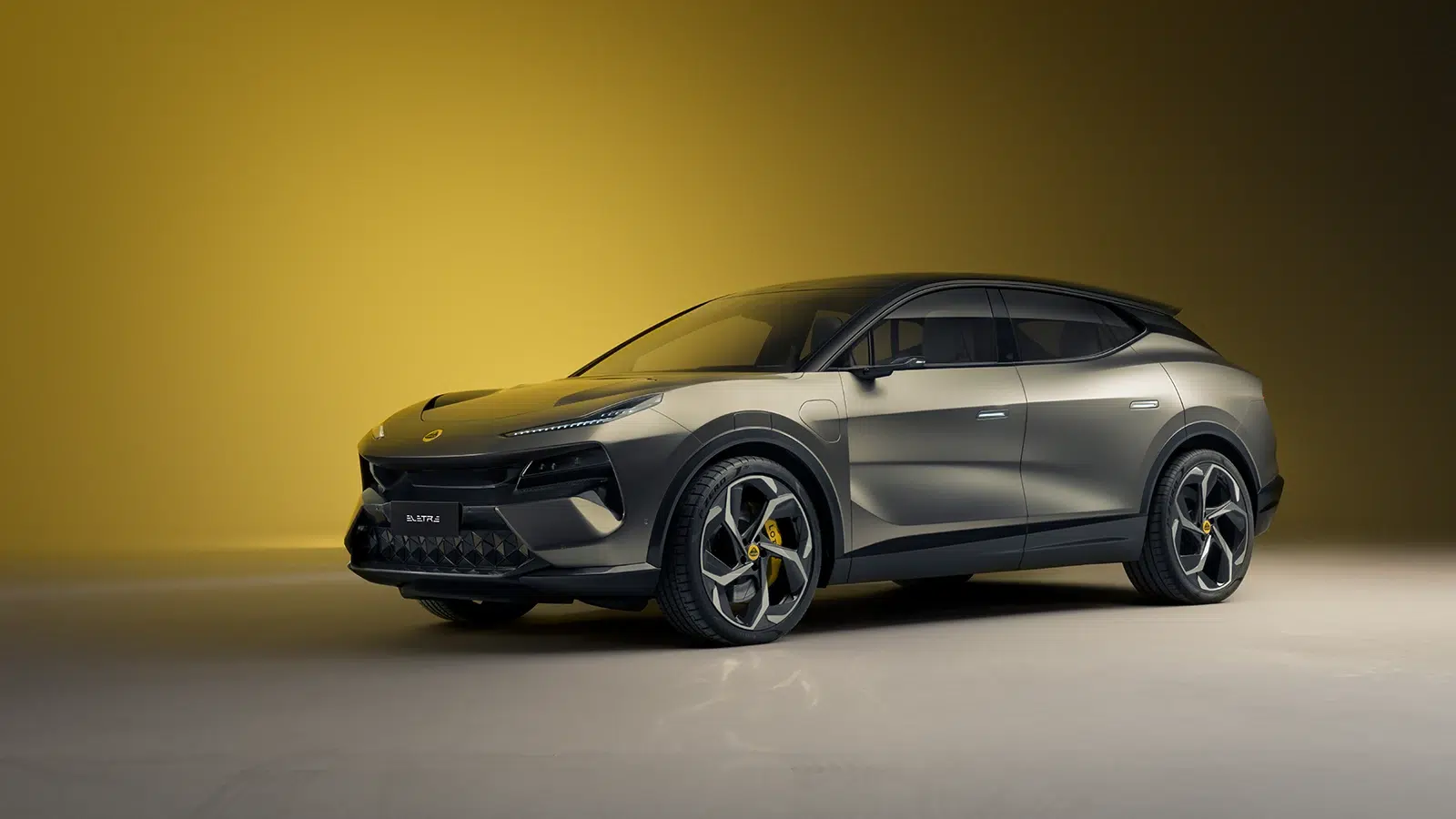 Silberner Lotus Eletre Elektro-SUV von vorne links vor gelbem Hintergrund.