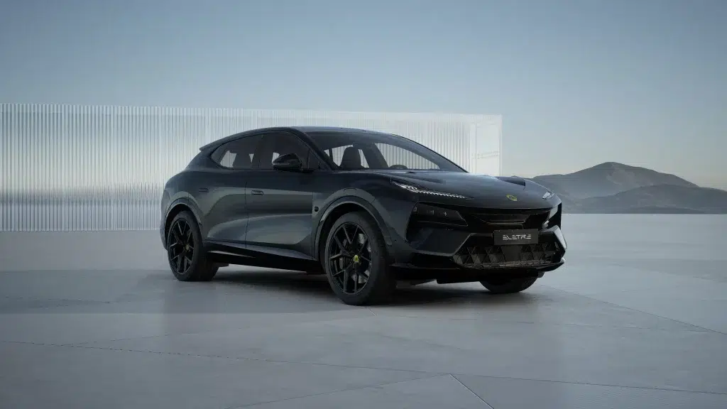 Dunkler Lotus Eletre Elektro-SUV auf Betonfläche vor moderner Fassade und Bergen.