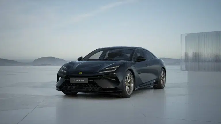 Lotus Emeya 600 GT SE in Stellar Schwarz auf einer Betonfläche vor Bergen und einem modernen Glasgebäude.