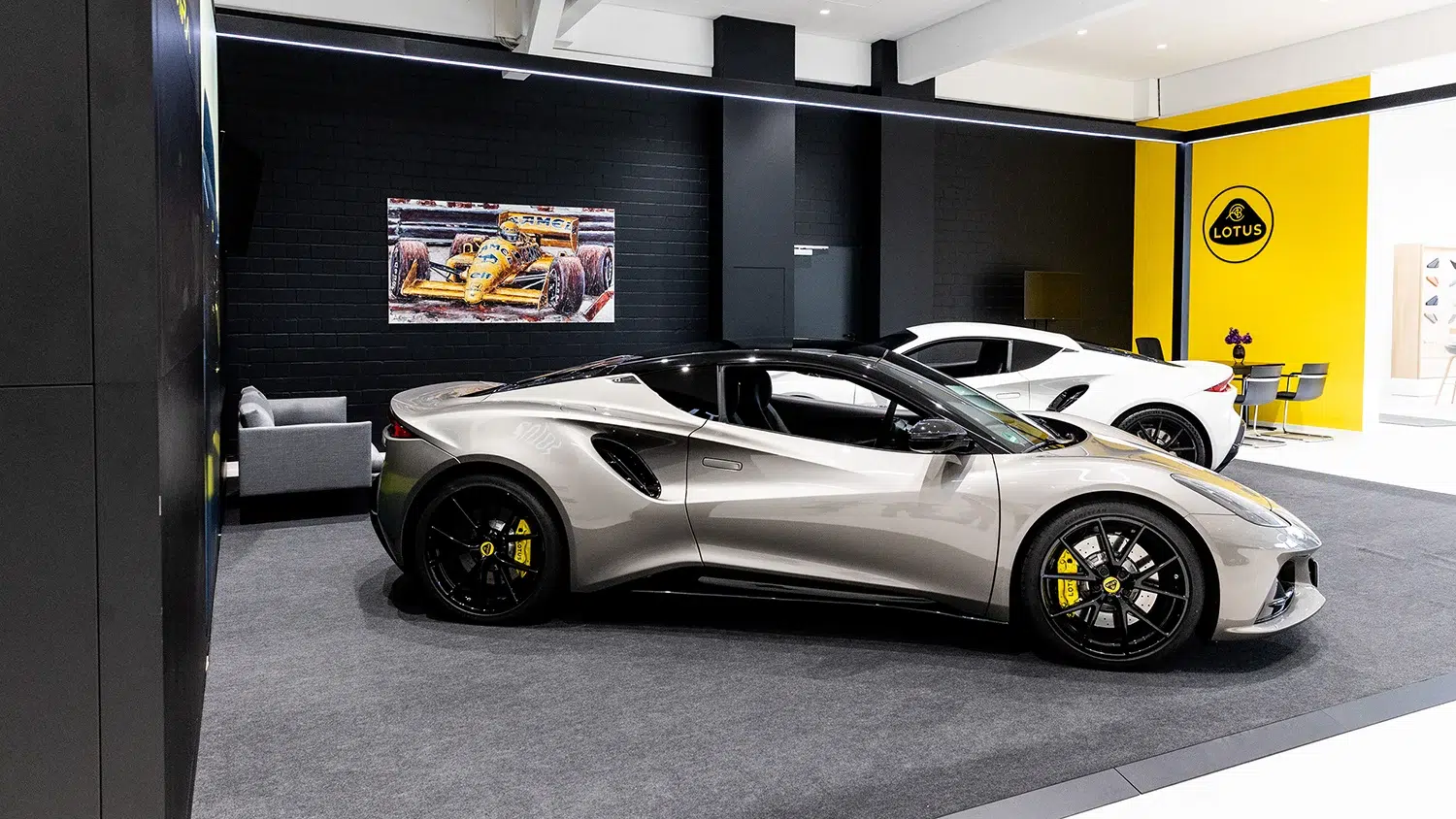 Lotus Showroom mit zwei Sportwagen, dem Lotus Logo und einem F1-Wandgemälde.